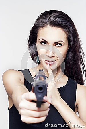 Young woman holding a gun saying shh Stock Photo