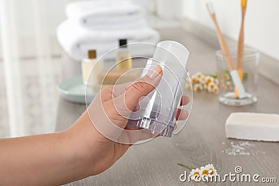 Young woman holding crystal alum deodorant at wooden table, closeup Stock Photo