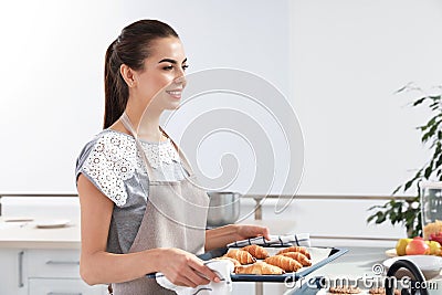 Young woman holding oven sheet with homemade croissants in kitchen Stock Photo