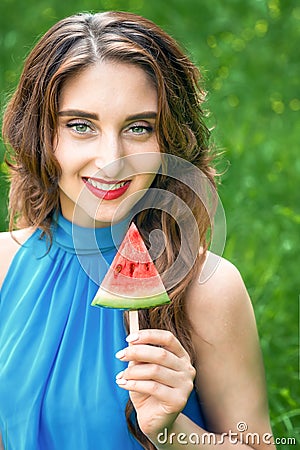 Young woman is holding piece of watermelon like ice cream on a green nature background Stock Photo