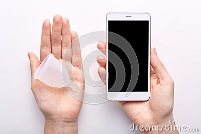 Young woman holding smartphone with blank screen in one hand and white clean menstrual cup, checking rules of usage reading Stock Photo