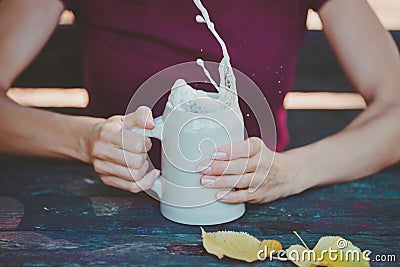 Young woman holding stein clay beer mug with fresh splashing beer in her hands Stock Photo