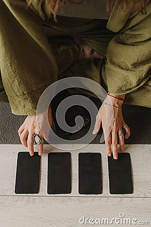 Young Woman holding Tarot cards and sitting in lotus pose on yoga mat, relaxed with closed eyes. Mindful meditation concept. Stock Photo