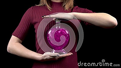 Young woman holds a bottle with a love potion. Glass bottle in the form of a heart with pink liquid. Valentine`s Day is Stock Photo