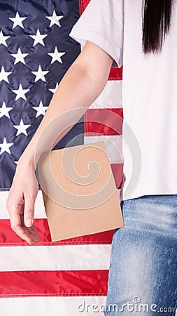 Young woman holds empty cardboard with Space for Text sign against American flag on background. Girl protesting anti-abortion laws Stock Photo