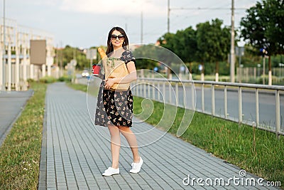 A young woman holds a grocery bag and a glass of coffee. The concept of shopping, eco shopping, lifestyle Stock Photo