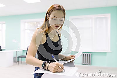 Young woman holds a salon for the care of hands and nails signs papers, puts a signature Stock Photo