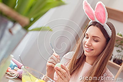 Young woman at home easter celbration concept in a bunny ears sitting coloring eggs painting dots Stock Photo