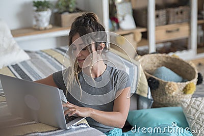 Young woman at home laying on the floor studying with laptop computer and sofa desktop - happy lifestyle female Stock Photo