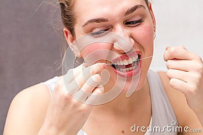 Young woman hurting herself in using dental floss for hygiene Stock Photo