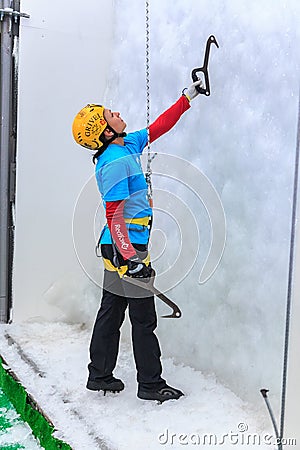 Young woman ice climber about to climb ice wall at ice climbing side-show attraction in Olympic Editorial Stock Photo