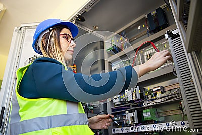 Young female maintenance engineer testing voltage with digital multimeter Stock Photo