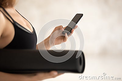 Young woman, instructor holding yoga mat, using phone close up Stock Photo