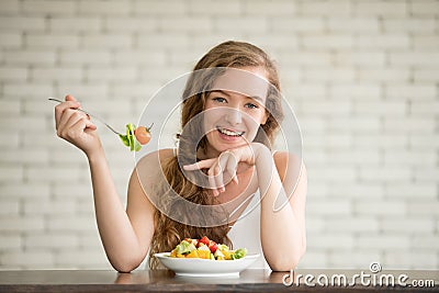 Young woman in joyful postures with salad bowl on the side Stock Photo