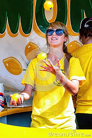 Young woman juggles three lemons in a lemonade stand Editorial Stock Photo