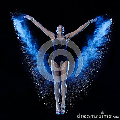 Young woman jumping in blue powder cloud Stock Photo