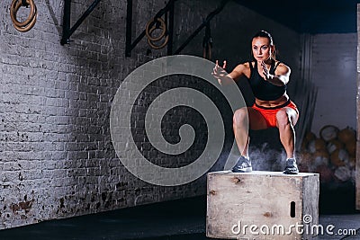 Woman jumping box. Fitness woman doing box jump workout at cross fit gym. Stock Photo