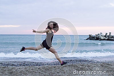 Young woman jumping happy at the beach, working out Stock Photo