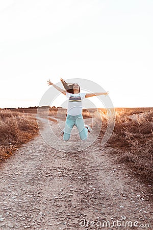 Young woman jumping at sunset in the field Stock Photo