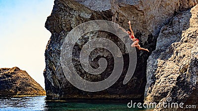 Young woman jumping to the sea from a cliff Editorial Stock Photo