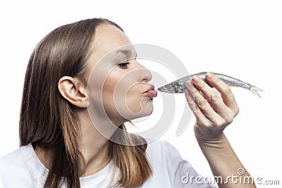 A young woman kisses a small raw fish. Health, vitamins and natural food. Close-up. Isolated on white background. Profile view Stock Photo