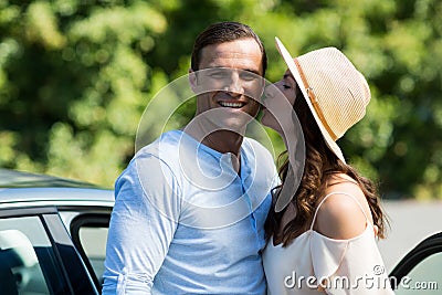 Young woman kissing man by car Stock Photo