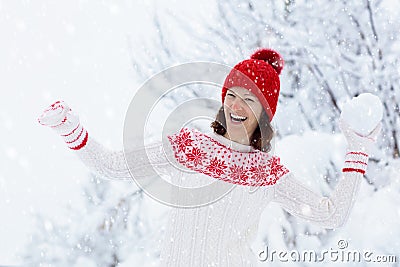 Young woman in knitted sweater playing snow ball fight in winter. Girl in family snow balls game. Female in knit handmade hat and Stock Photo