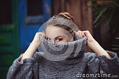 Young woman in a knitted turtleneck sweater covering her face. Close up Stock Photo