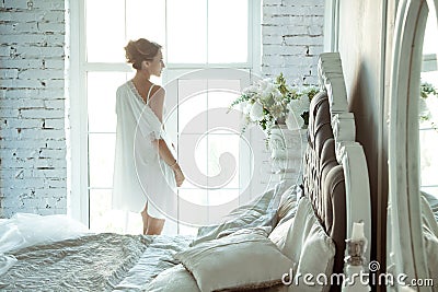 Young woman in lace lingerie standing in front of huge window Stock Photo