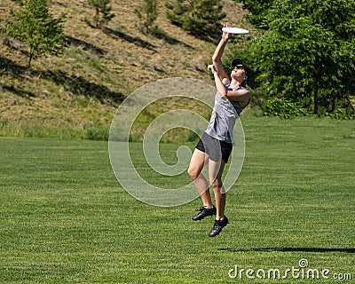Young woman leaps for flying disc Stock Photo