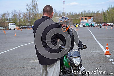 A young woman is learning to ride a motorbike in a motorcycle school. She is taught by a teacher Stock Photo
