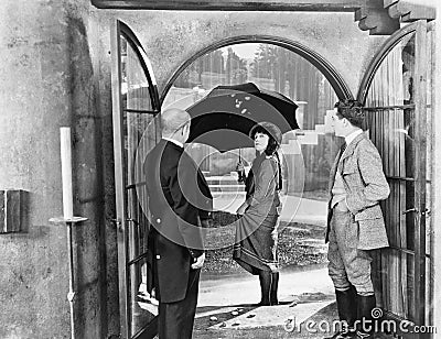 Young woman leaving a house with an umbrella to walk in the rain Stock Photo