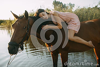 Woman lies astride a horse at river Stock Photo