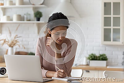 Young woman listen to lesson on pc check written records Stock Photo