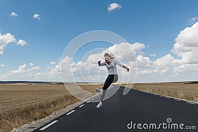 Young woman jumping on the road on nowhere Stock Photo