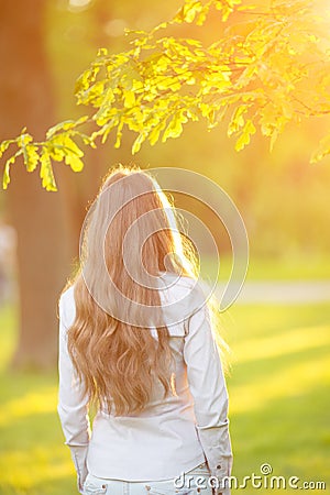 Young woman with long hair turned back outdoors in sun light Wa Stock Photo