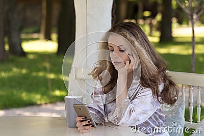 Young woman with long light hair dressed in silk peignoir is loo Stock Photo