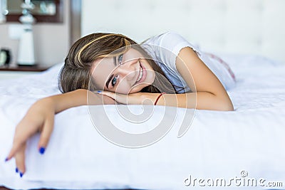 Natural beauty. Young woman looking at camera and smiling while lying on the bed at home Stock Photo
