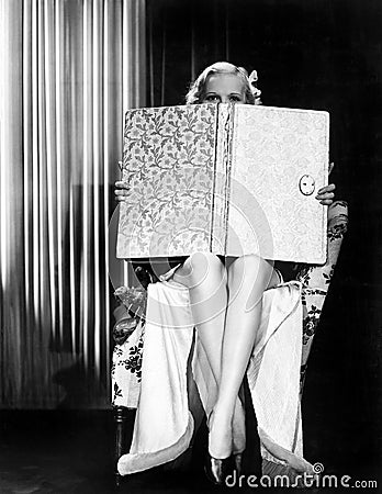 Young woman looking over top of an oversized book Stock Photo