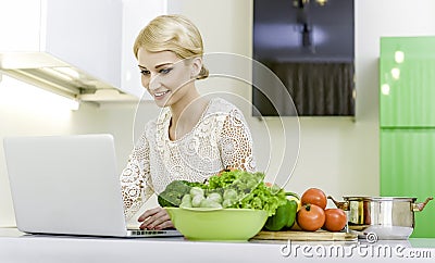 Young woman looking for a recipe on the laptop computer in the kitchen Stock Photo