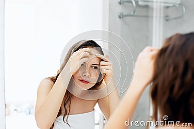 Young woman looking and squeeze pimples on a face. Skin care. Problem with skin girl, acne on forehead.Beauty Stock Photo