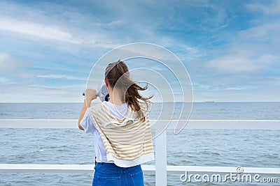 A young woman looks through coin binoculars, rear view. Stock Photo