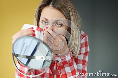 Young woman looks in mirror and bleeds from nose Stock Photo