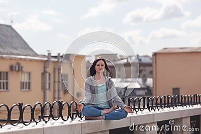Young woman in a lotus position on the parapet Stock Photo