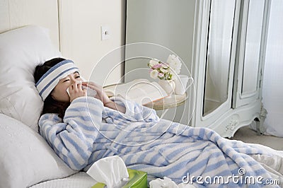 Young woman lying on bed with common cold Stock Photo