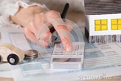 Young woman makes some calculations. Small paper house, coins, c Stock Photo