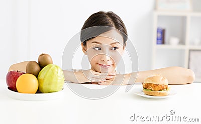 Young woman making choice between healthy and harmful food Stock Photo