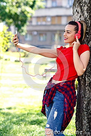 Young woman making video call via smartphone and headphones Stock Photo