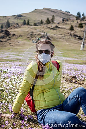 Young woman in mask and sunglasses walking outside Stock Photo