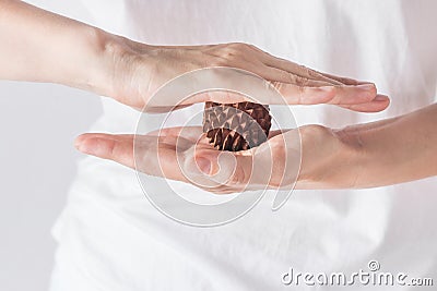 Young woman massage therapist in white shirt holds in hands spiky physio ball from sandal wood for relaxation ailment pain Stock Photo